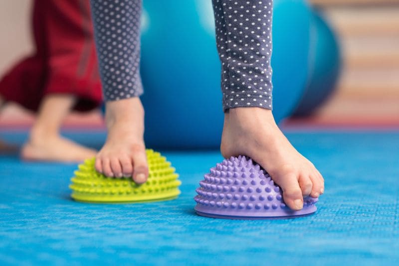Kindervoeten balanceren op twee gekleurde balanskussens.
